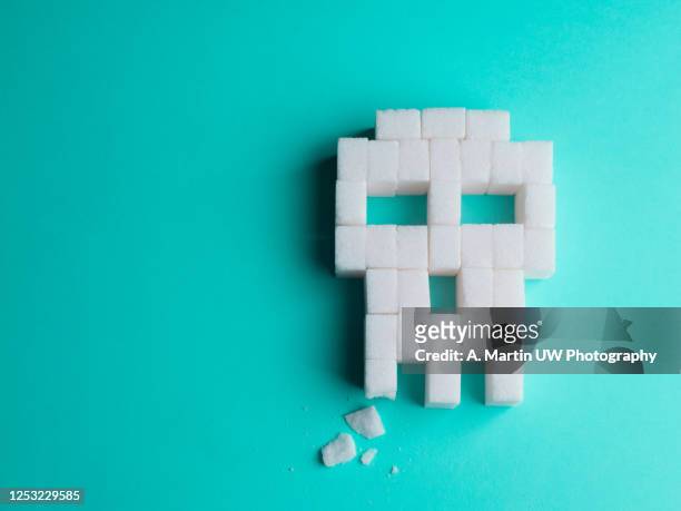 skull made of sugar cubes with a broken tooth. concept of tooth decay. - glucose stockfoto's en -beelden
