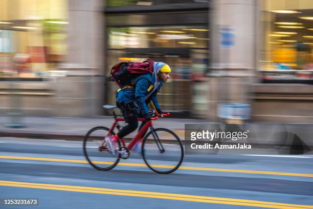mixed race bicycle messenger fietsen op city street - bike messenger stockfoto's en -beelden