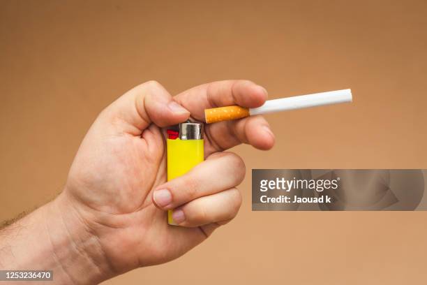 close up view of a man holds a cigarette, and a steel gas lighter. - feuerzeug stock-fotos und bilder