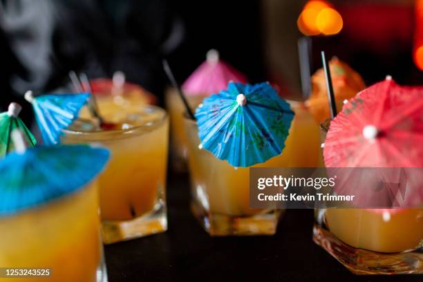 yellow cocktails with colorful umbrellas - cocktail umbrella stock-fotos und bilder