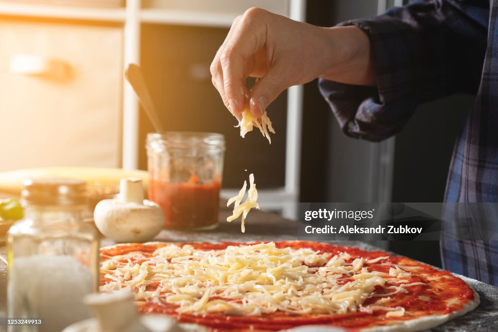 Cooking Italian Vegetarian Pizza With Vegetables And Mushrooms At Home, On A Wooden Table. The Woman Puts And Sprinkles Grated Cheese On The Dough. Step-by-step instructions, Do it Yourself. Step 4.