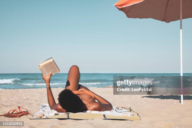 afro italienische frau lesen ein buch und entspannen am strand im sommer - beach book reading stock-fotos und bilder
