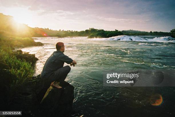 jeune homme regardant fixement la source du nil de fleuve - eau douce photos et images de collection