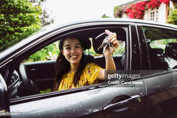 cheerful young woman showing the keys of her new car - achat photos et images de collection