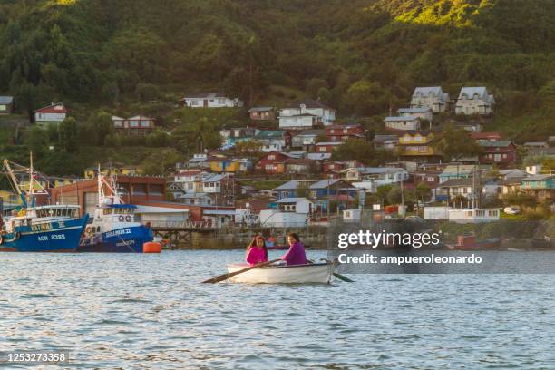 un par de turistas en un barco en medio del océano en casas de palafitos en puerto montt, chile - castro isla de chiloé fotografías e imágenes de stock