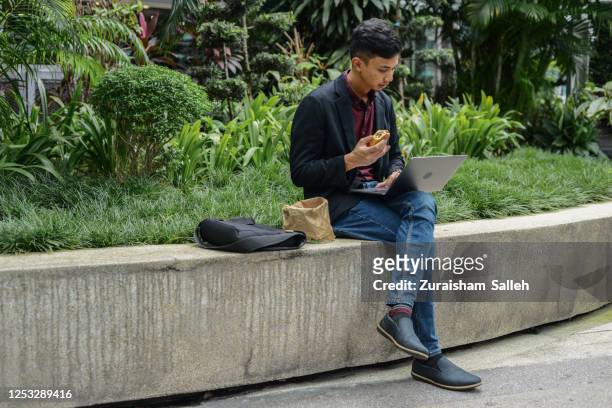 asian young business man having lunch outdoors - business lunch outside stock pictures, royalty-free photos & images