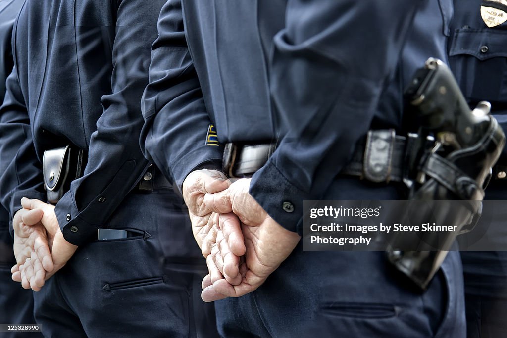 Officers standing with hands behind