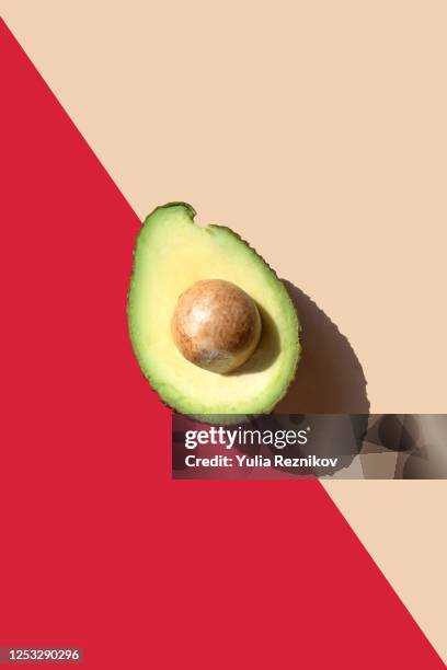 close-up of avocado on red-beige background - rijp stockfoto's en -beelden