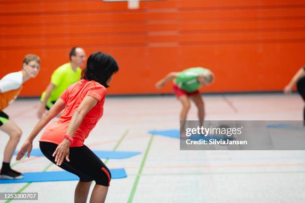 gruppe von erwachsenen, die in der schulturnhalle trainieren - school gymnastics stock-fotos und bilder