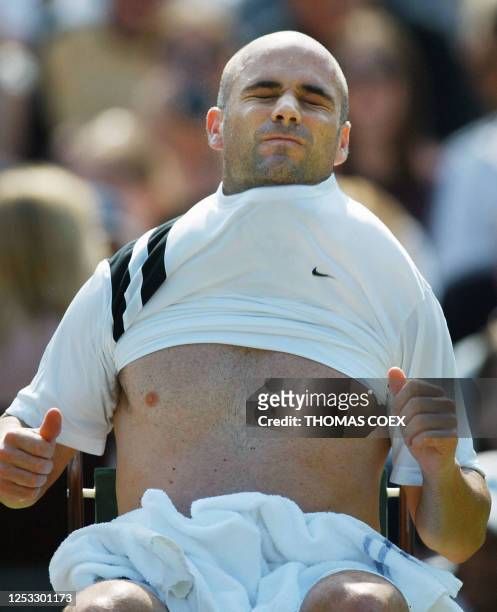 Andre Agassi of the US wipes changes his shirt between games during his match with Lars Burgsmuller of Germany at the Wimbledon Tennis Championships...