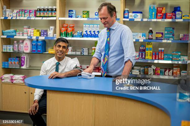 Britain's Prime Minister Rishi Sunak reacts as he has his blood pressure checked by pharmacist Peter Baillie, during a visit to a GP surgery and...