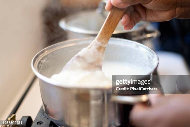 close up woman stirs maize meal cooking in a pot with wooden spoon - cornmeal stock pictures, royalty-free photos & images