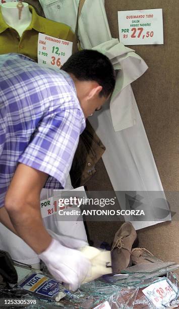 Clothing store worker after a bomb exploded in front of McDonald's in Rio de Janeiro, 18 October 2001. Un empleado retira vidrios rotos de una...