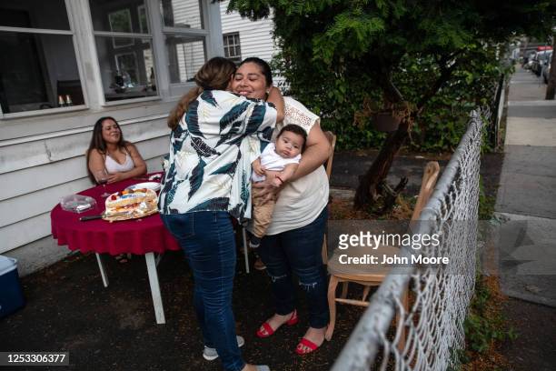 Zully holds her son Neysel, 10 weeks, while embracing elementary school teacher Luciana Lira following a dinner celebrating Neysel's three month...