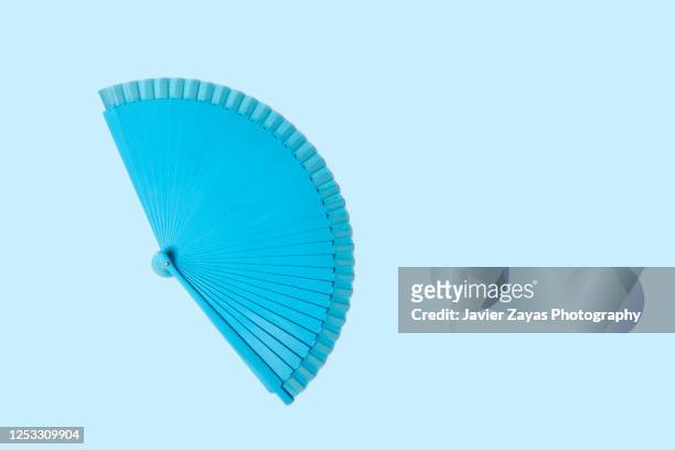 blue folding fan over blue background - waaier stockfoto's en -beelden