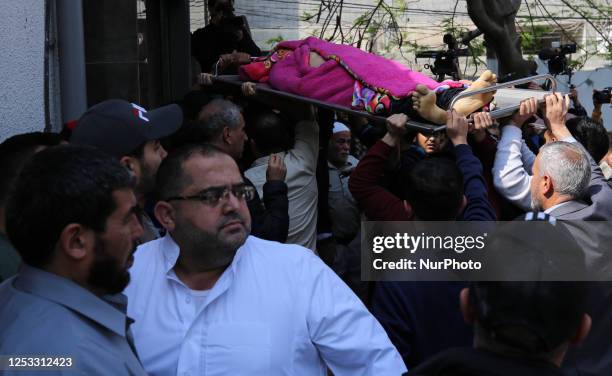 Mourners carry the body of a Palestinian boy killed in an Israeli air strike from the mortuary ahead of his burial in Gaza City on May 9 following...