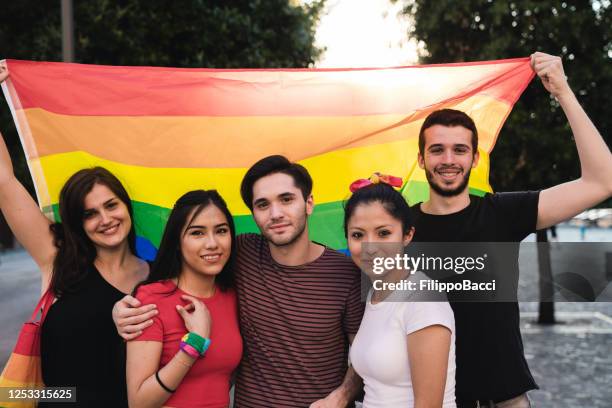 cinco amigos juntos contra uma bandeira do arco-íris durante um evento de orgulho lgbtqi - polyamory - fotografias e filmes do acervo