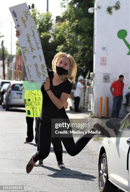 Mother with a face mask jumps with her congratulatory message for her graduate during graduation from the 'Instituto de Aprendizaje Creativo' on June...