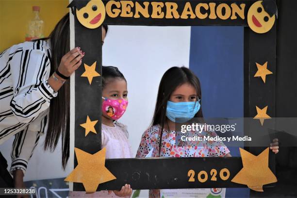 Two girls with face mask take a picture with a commemorative frame during graduation from the 'Instituto de Aprendizaje Creativo' on June 29, 2020 in...