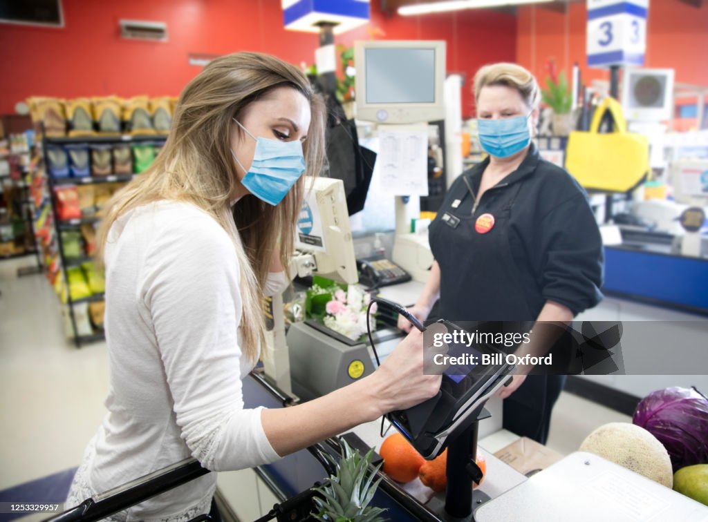 Woman grocery shopping wearing surgical mask due to Covid-19 virus