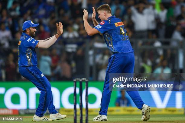 Mumbai Indians' Cameron Green celebrates with Rohit Sharma after taking the wicket of Royal Challengers Bangalore's Faf du Plessis during the Indian...