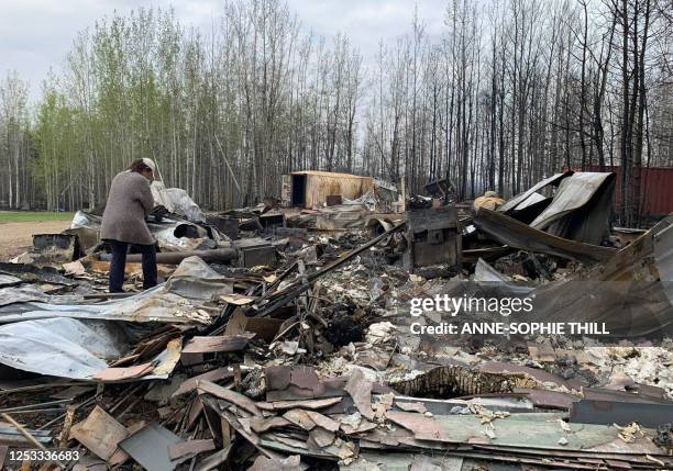 Cheryl Harris walks through the debris of her work place, Pembina River Tubing, in Entwistle, Alberta, Canada, on May 9, 2023. Canada struggled on...
