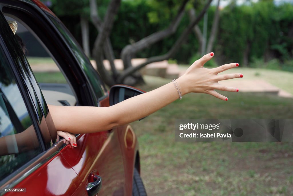 Woman at road trip enjoying with hand on the road breeze