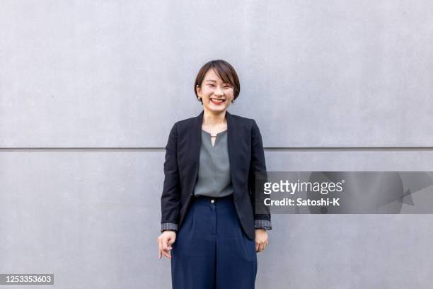 portrait of business woman standing on simple gray wall - only japanese stock pictures, royalty-free photos & images