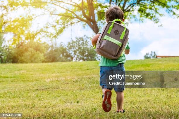 学校に戻って歩いているバックパックを運ぶ小さな男の子 - 子供のみ ストックフォトと画像