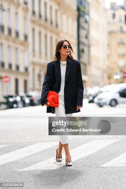 Geraldine Boublil wears Moscot sunglasses, a white dress from Basilika, a Gauge 81 navy dark blue oversized blazer jacket, a red woven leather...