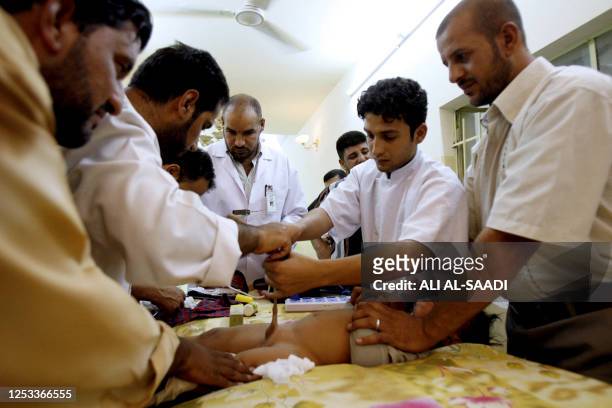 Iraqi doctors perform a circumcision 31 July 2006 at Baghdad's poor neighborhood of Sadr city. Shiite firebrand Moqtada al-Sadr's social committee...