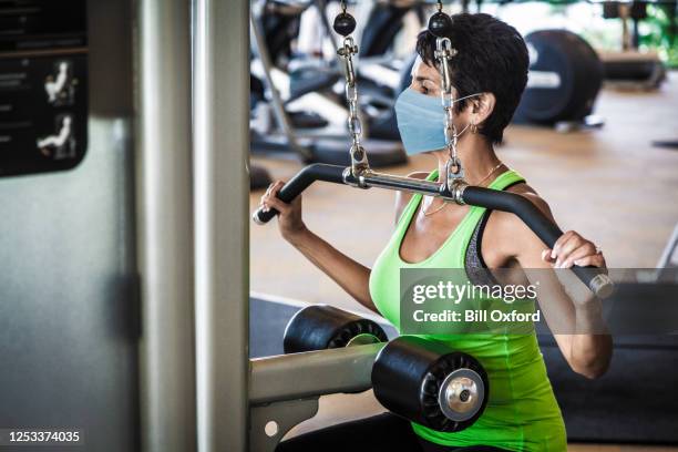 woman at gym wearing mask to prevent spread of covid-19 virus - gym covid stock pictures, royalty-free photos & images