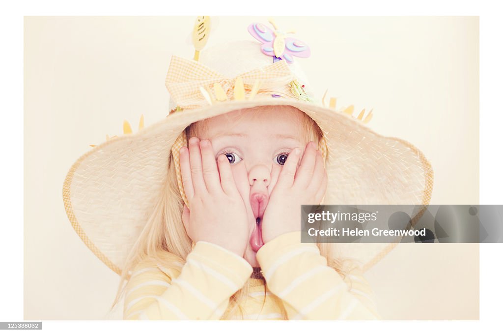 Young girl pulling faces in Easter bonnet