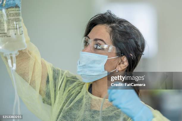 hispanic nurse hanging an iv bag - saline drip stock pictures, royalty-free photos & images