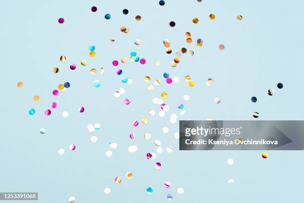 colored confetti flying in the blue sky. are small pieces or streamers of paper, mylar, or metallic material which are thrown at parades and celebrations. - fiesta fotografías e imágenes de stock