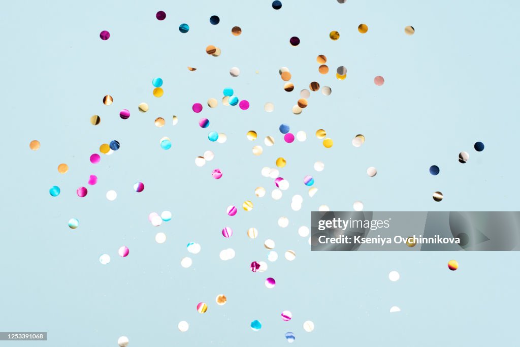 Colored confetti flying in the blue sky. Are small pieces or streamers of paper, mylar, or metallic material which are thrown at parades and celebrations.