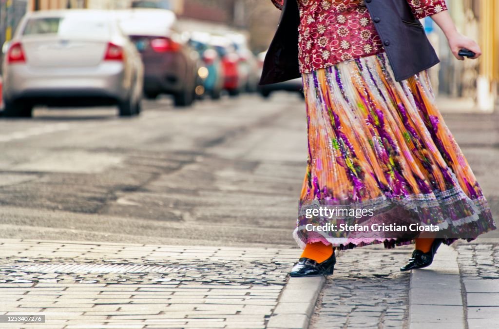 Women wearing a multicoloured dress crossing the street in rush