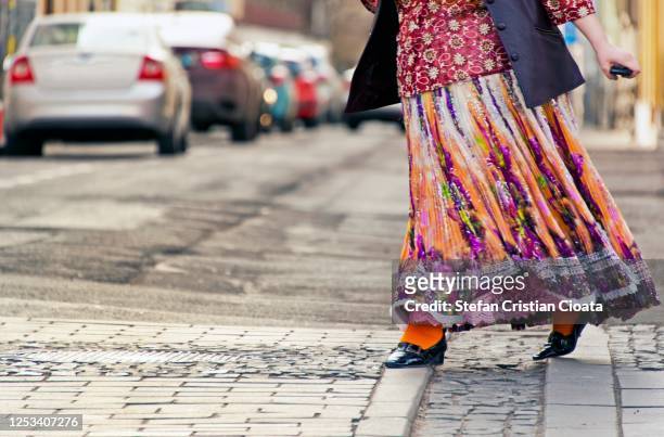women wearing a multicoloured dress crossing the street in rush - gipsy stock pictures, royalty-free photos & images