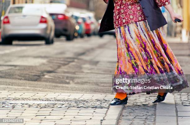 women wearing a multicoloured dress crossing the street in rush - romani people 個照片及圖片檔