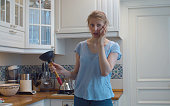 Confused woman in the kitchen with a plunger in her hands
