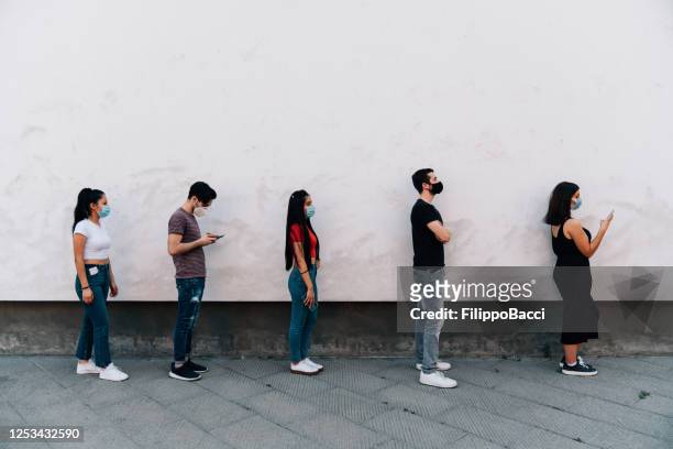 people waiting in line to enter in a store - social distancing concept - social distancing stock pictures, royalty-free photos & images