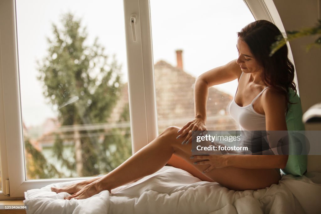 Side view of woman massaging her legs while relaxing