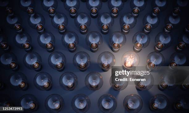 bombilla brillante que destaca de la multitud - bombilla de bajo consumo fotografías e imágenes de stock