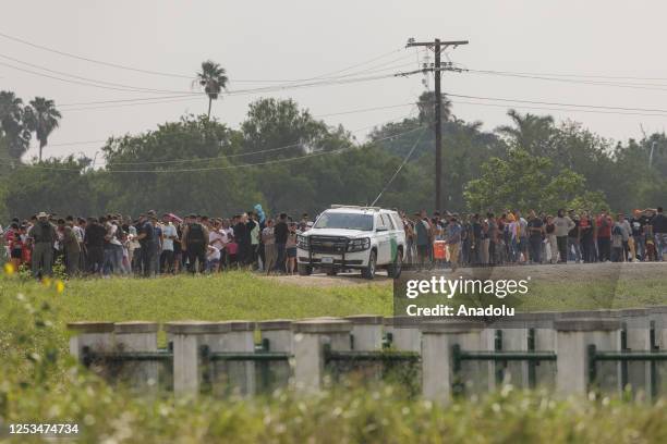 United States Border Patrol vehicle drives by a line of migrants waiting to begin processing to seek asylum on May 9, 2023 in Brownsville, Texas,...