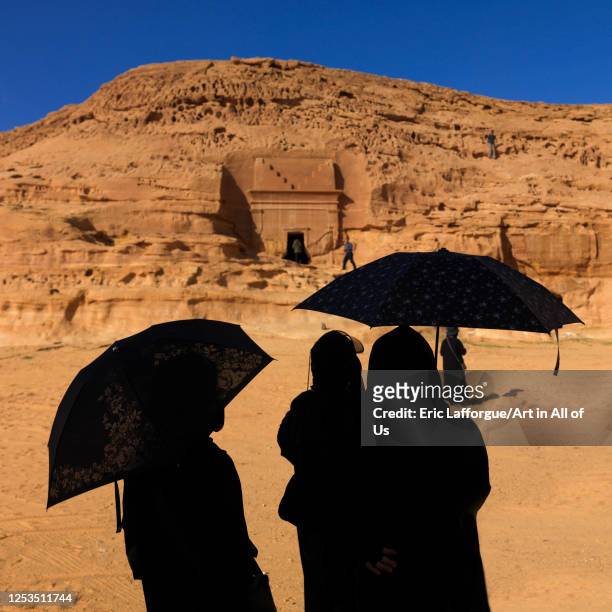 Tourists with umbrellas in madain saleh archaeologic site, Al Madinah Province, Alula, Saudi Arabia on January 23, 2010 in Alula, Saudi Arabia.