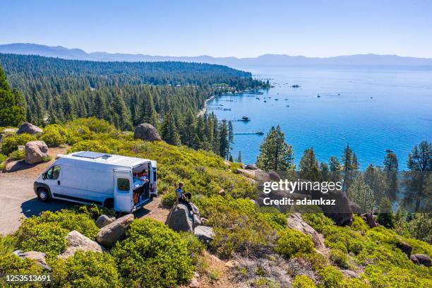junges paar parkte van an einem aussichtspunkt des lake tahoe - camper van stock-fotos und bilder