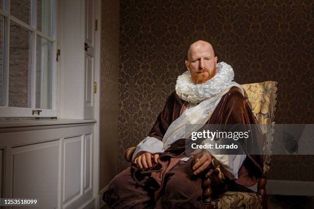 roodharige traditionele nederlandse mens die een boek door kaarslicht leest - dutch culture stockfoto's en -beelden