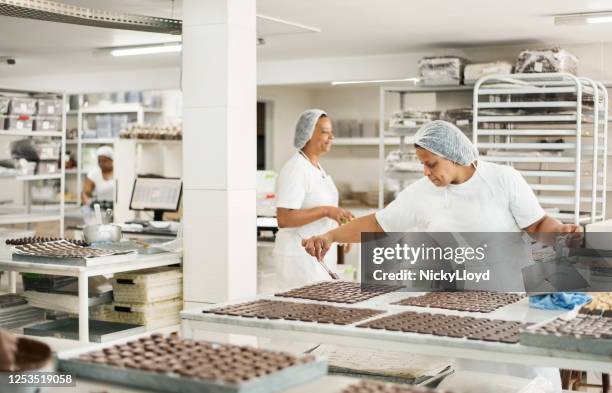 professional chocolatiers working in chocolate factory - chocolate factory stock pictures, royalty-free photos & images