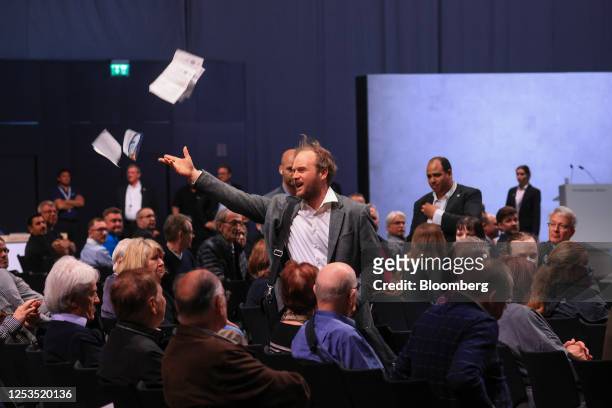 Protester throws papers at the Volkswagen AG annual general meeting in the CityCube Berlin conference centre in Berlin, Germany, on Wednesday, May...