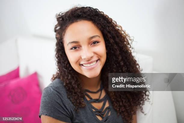 mooie donkerbruine tiener die bij camerazitting op laag thuis glimlacht - one teenage girl only stockfoto's en -beelden